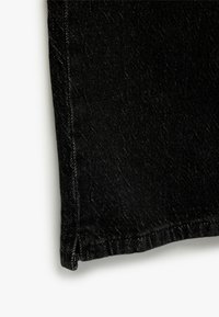 Tejido de mezclilla negro, con un sutil brillo, con un dobladillo recto y costuras cosidas, que muestra una textura suave y un tono oscuro.