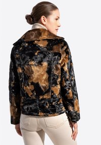 Kurtka z futra syntetycznego w czarno-brązowy abstrakcyjny wzór, z kołnierzem i miękką teksturą. Projekt charakteryzuje się dopasowanym krojem, bocznymi kieszeniami oraz paskiem w talii.