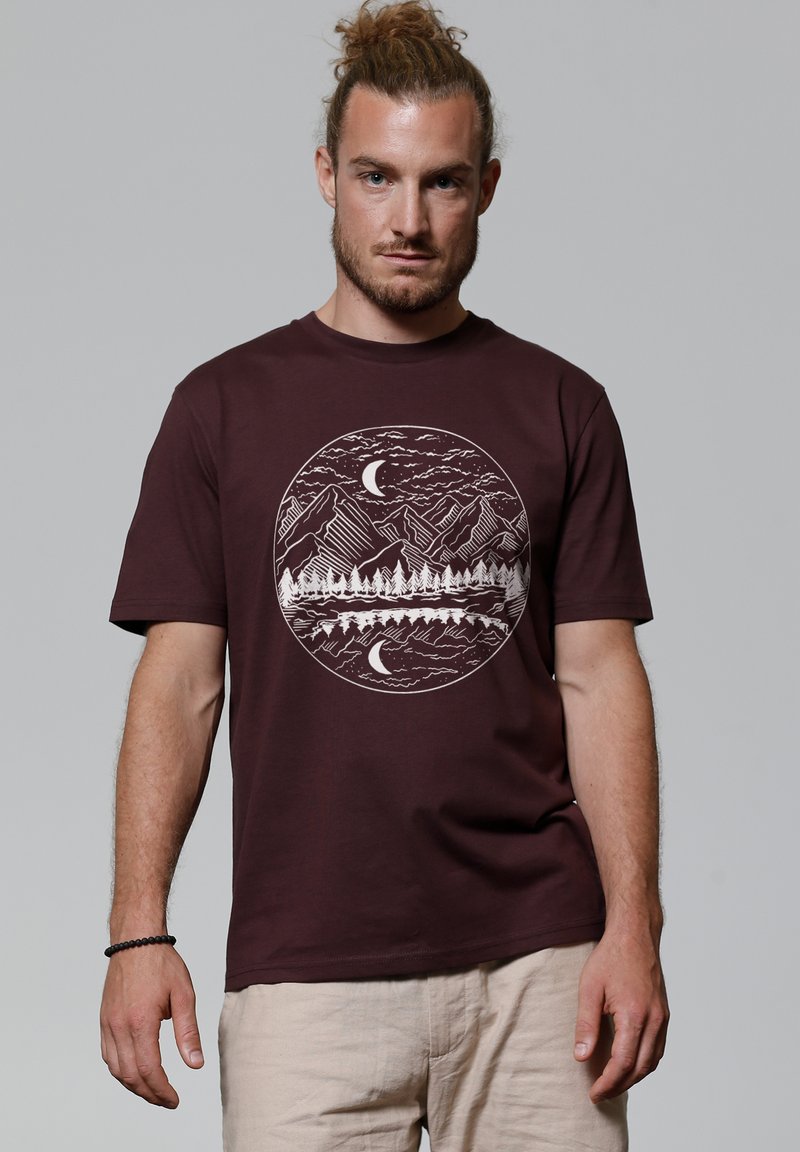 T-shirt en coton bordeaux avec un graphique circulaire blanc représentant des montagnes, des arbres et une lune. Manches courtes, design à col rond.