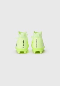 Botas de fútbol amarillas brillantes con un collar ajustado, parte superior de malla y acentos traseros. Presenta el texto "PHANTOM" en el talón y una suela texturizada.