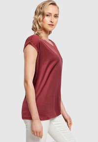 Burgundská v-neck tričko s krátkymi rukávmi, vyrobené z mäkkej látky; skombinované s bielymi priliehavými nohavicami s hladkou textúrou a voľným strihom.
