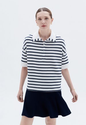 Marineblau-weiß gestreiftes kurzärmeliges Poloshirt mit klassischem Kragen und Knopfleiste, kombiniert mit einem dunklen Rock. Glatte Stricktextur.