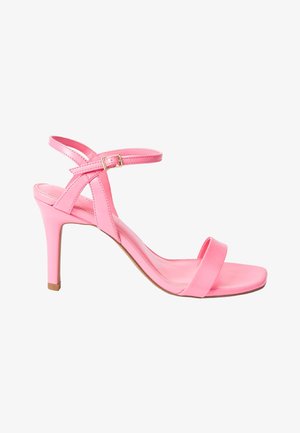 Roze hoge hak sandaal met een glanzende afwerking. Heeft een enkele brede band over de tenen en een kruisband voor de enkel met een gesp.
