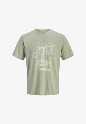 Camiseta verde claro con un dibujo en línea blanca de una escena de cafetería al aire libre, que incluye mesas, sillas, sombrilla y las palabras "Hora de Café" y "Premium".