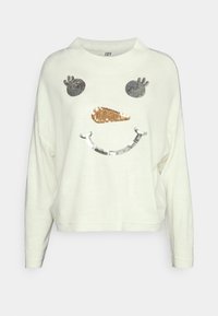 Biały sweter z długim rękawem z ozdobnym wzorem przedstawiającym twarz bałwana, w tym ciemne oczy, złoty nos w kształcie marchwi i srebrny uśmiech.