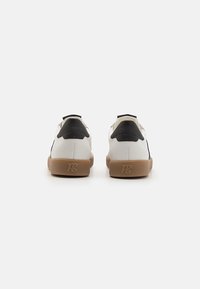 Weiße und schwarze Sneaker, Obermaterial aus strukturiertem Leder, gepolsterter Kragen, Sohle aus Gummi, mit Logodetail an der Ferse. Rückansicht dargestellt.