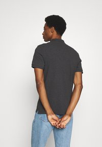 Donkergrijze polo met korte mouwen, een klassieke kraag en omgeslagen manchetten, gemaakt van een gladde, gestructureerde stof. Casual pasvorm en achteraanzicht.