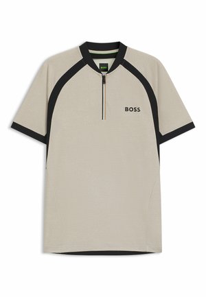 Beige polo skjorte med en svart glidelåskrage, kontrasterende svarte skulderpaneler, teksturert stoff og subtil logo på brystet.