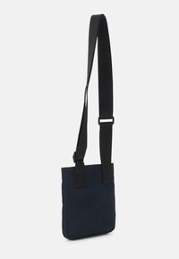 Borsa a tracolla in tessuto blu navy con forma rettangolare piatta, tracolla nera regolabile e design minimalista.