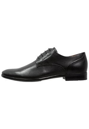 Chaussure habillée pour homme en cuir noir avec lacets, talon bas, et logo Calvin Klein sur le côté, vue de l'extérieur.