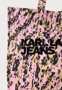 Vászon bevásárlótáska, rózsaszín, fekete és barna absztrakt leopárdmintával. Tartalmazza a "KARLLA JEANS" feliratot vastag fekete betűkkel.
