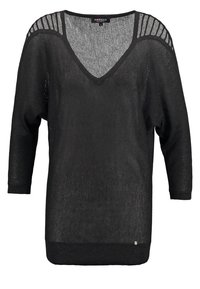 Czarny dziany sweter z dekoltem w serek, długimi rękawami typu nietoperz oraz teksturowanymi akcentami na ramionach. Posiada jednolity ściągacz u dołu oraz subtelny połysk.