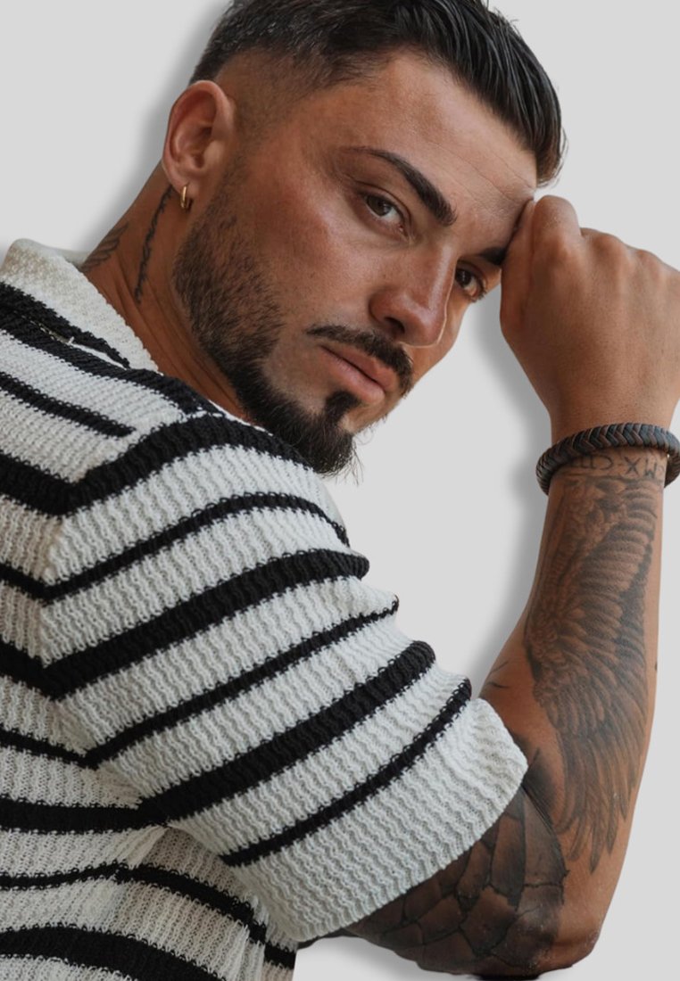 Black and white striped knitted sweater with a textured finish. Features short sleeves and a crew neckline. Forearm tattoo visible.