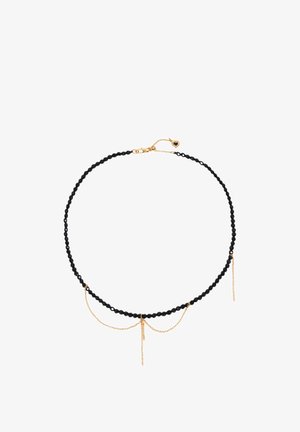 Czarny naszyjnik z koralików z ozdobami w postaci złotych łańcuszków, w tym małych zwisających łańcuszków oraz zapięcia w kształcie serca.