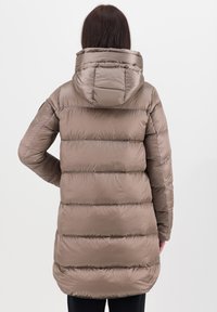 Lang, gewatteerde jas in taupe met een capuchon. Kenmerkt zich door horizontale quilten, een gladde textuur en een licht afgeronde zoom aan de achterkant.