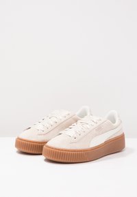 Baskets en suede beige clair avec un accent en simili cuir blanc, bout arrondi, semelle épaisse en caoutchouc gomme et lacets plats en satin.