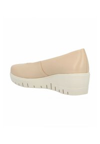 Zapato sintético color beige sin cordones, con punta redondeada, que presenta una suela blanca gruesa y costuras sutiles en la parte superior para mayor textura.