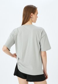 Lichtgrijze oversized t-shirt met korte mouwen, ronde halslijn en een ontspannen pasvorm. Zacht materiaal met een gladde textuur. Geen zichtbare patronen.