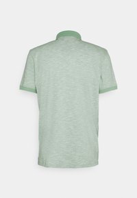 T-shirt polo vert avec un tissu texturé, un col et des accents de poignet unis. Le design est simple, avec des manches courtes et une coupe décontractée.