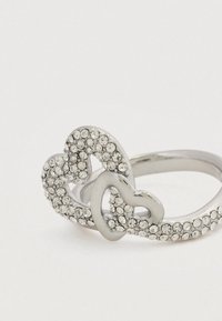 Ασημένιο δαχτυλίδι με δύο διαπλεκόμενες καρδιές στολισμένες με διαφανείς στρας, με γυαλιστερό φινίρισμα και λεία σχεδίαση μπάντας.