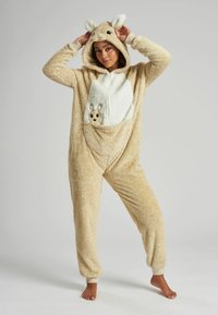 Tan pluche onesie met een witte buik, kap met oren en een voorzakje met een klein dierenontwerp. Boorden bij de polsen en enkels.
