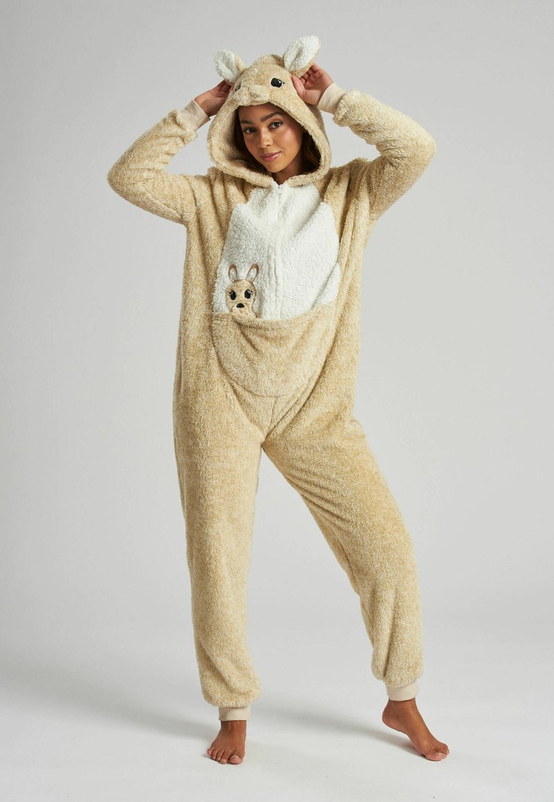 Tan pluche onesie met een witte buik, kap met oren en een voorzakje met een klein dierenontwerp. Boorden bij de polsen en enkels.
