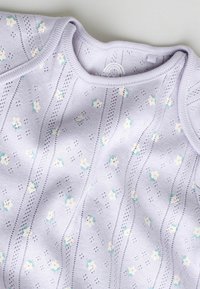 Lyse lilla baby-body med små hvide og pink blomster og lodrette øjestriber, blødt strikstof.