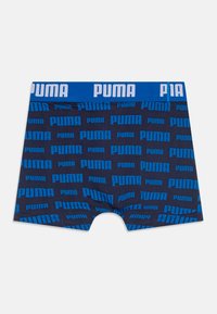 Boxer shorts azul marinho com padrão repetido do logótipo "PUMA" em azul claro. Apresenta uma cintura larga azul com letras brancas. Tecido macio e elástico.