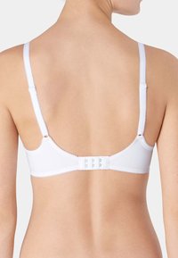 Witte beha met verstelbare bandjes, een gladde textuur en een haak-en-oogsluiting. De band en bandjes zijn afgewerkt met gegolfde randen.