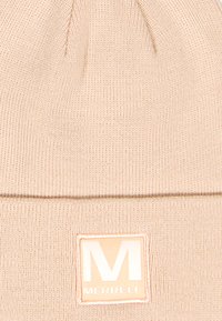 Cappello di maglia morbida color pesco con risvolto. Presenta un motivo testurizzato e una patch rettangolare con il logo Merrell arancione e bianco.