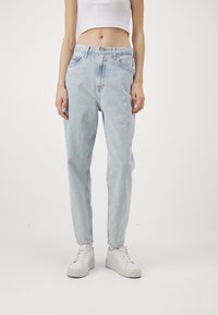 Ljusblå hög midja jeans med en avslappnad passform, med knappstängning, fem fickor och en blekt denimtextur. Tillsammans med vita sneakers.