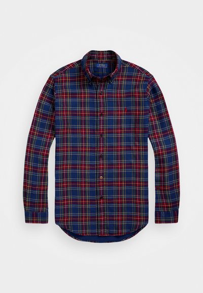 Chemise à carreaux dans des tons bleu marine, rouge et jaune. Manches longues, col boutonné, ourlet courbé, avec un petit logo sur la poitrine. Tissu en coton.