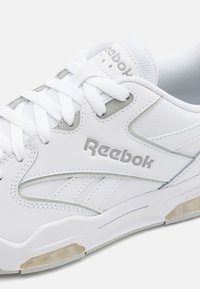 Baskets blanches Reebok avec dessus en cuir et mesh, ornées d'accents argentés, bout rond et lacets texturés. Amorti d'air dans la semelle.