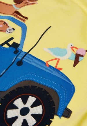 Blauwe tractor met zwarte wielen, een bruine hond die erin rijdt, en een witte en blauwe meeuw die een ijshoorntje vasthoudt op een gele achtergrond.