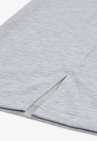 Λεπτομέρεια από ανοιχτό γκρι ύφασμα που δείχνει μια κοντινή απεικόνιση του τελειώματος ενός πουκάμισου με πλαϊνές σχισμές και λεία υφή, με αντίθετα σχέδια ραφής.