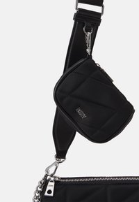 Svart vadderad axelväska med en avtagbar mini-påse, silverfärgad hårdvara och justerbar rem med en tryckknappskrok för fäste.