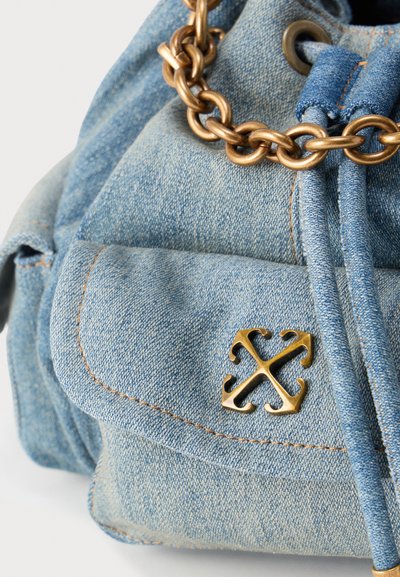 Τσέπη από τζιν με χρυσό μεταλλικό χερούλι αλυσίδα που αλληλοσυνδέεται και έμβλημα με σταυρωτή άγκυρα στη μπροστινή πτυχή.
