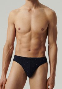 Granatowe męskie slipy o dopasowanym kroju, wykonane z miękkiego materiału, z małymi wzorami geometrycznymi i markowym pasem.