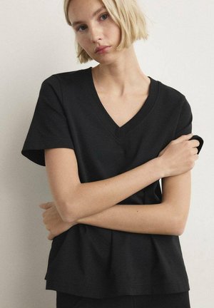 Schwarzes V-Ausschnitt-T-Shirt aus weicher Baumwolle, mit kurzen Ärmeln und lockerem Schnitt, der einen gerafften Saum für zusätzliches Volumen aufweist.