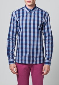 Koszula na długi rękaw zapinana na guziki, z niebiesko-jasnoniebieskim wzorem w kratę, kontrastującymi ciemnymi guzikami i kołnierzykiem typu spread.