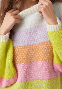 Pull en tricot présentant de larges rayures bleu clair, orange, rose et vert néon. La texture est douce avec un col côtelé épais.