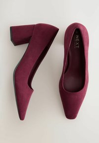 Décolleté in suede bordeaux con punta affilata, design elegante e tacco a blocco. L'interno presenta una fodera in tessuto liscio.