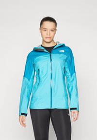 Teal vandtæt jakke med lynlås foran, hætte og grå detaljer. Har to sidelommer og justerbare manchetter. Glat, let tekstur.
