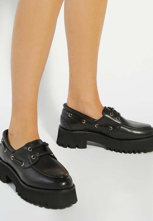 Zwarte leren schoenen met een chunky platformzool, voorzien van gouden ogen en veters. Glad oppervlak met een afgerond te ontwerp.