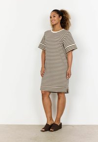 Striped dress in brown and cream, short sleeves, relaxed fit with side slits, worn with brown woven slide sandals on a smooth surface.