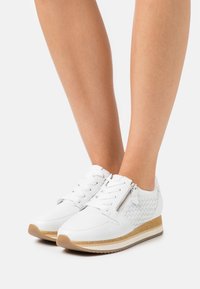 Vita lädersneakers med vävd sidodetalj, en texturerad dragkedja och en ljusbrun plattformssula.