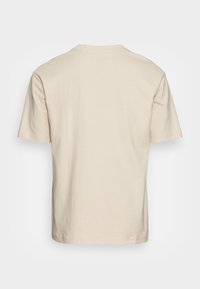 T-shirt beige à manches courtes en coton doux, avec un col rond classique et un design uni sans motifs ni logos.