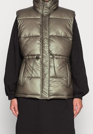 Chaleco tipo puffer en color caqui con cuello alto, bolsillos laterales y cintura ajustable con cordón. Textura brillante y acolchada con un diseño ligero.