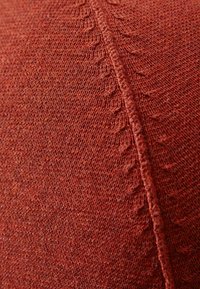 Strickstoff in einem rötlich-braunen Farbton mit einer strukturierten Oberfläche, die entlang der Nähte ein dezentes Muster aufweist und ein glattes, weiches Finish hat.