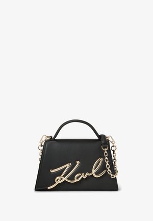 Juodas odinis rankinukas su struktūruota forma, auksinėmis grandinėmis ir ryškiu auksiniu "Karl" logotipu priekyje. Lygus paviršius ir elegantiškas dizainas.